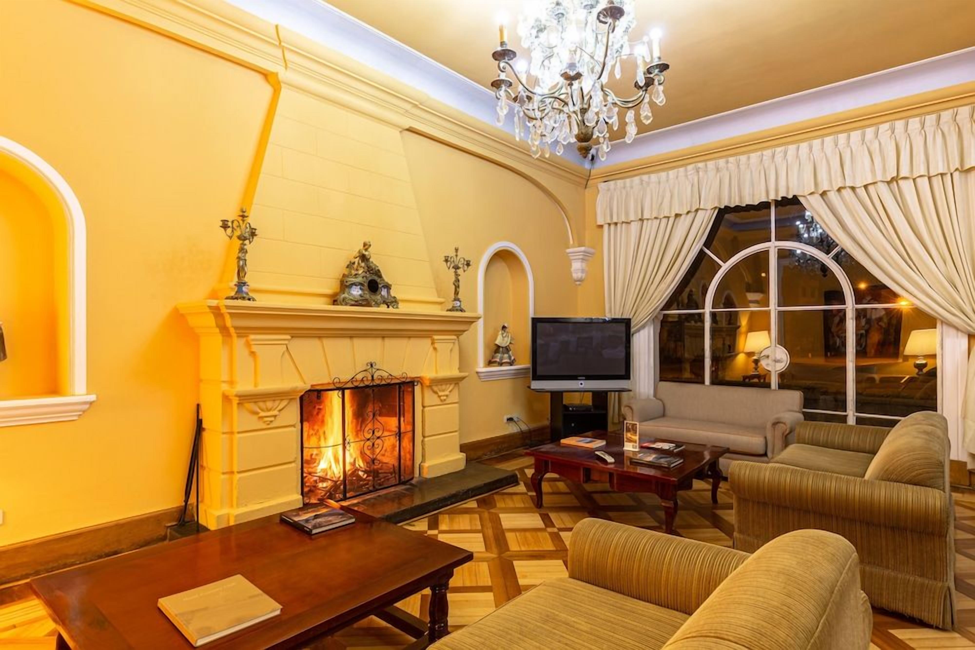 Una habitación con chimenea, televisor, sofá y candelabro.
