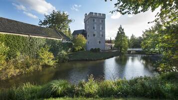 A castle-like building with a tower, surrounded by a moat and lush greenery.