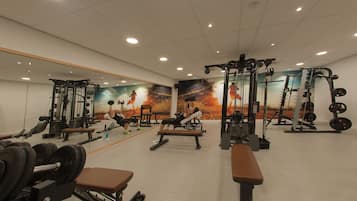 A gym with various exercise equipment, including benches, dumbbells, and weight machines.