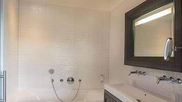 A modern bathroom with a bathtub, a vanity with a mirror, and dark wooden cabinets.