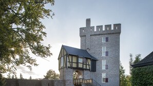 Un edificio de estilo castillo con fachada de piedra, una gran torre central y una entrada simétrica.