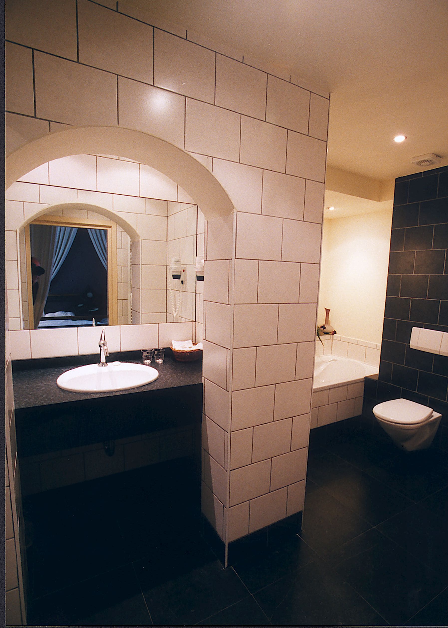 A bathroom with a white sink, a mirror, a bathtub, and a toilet.