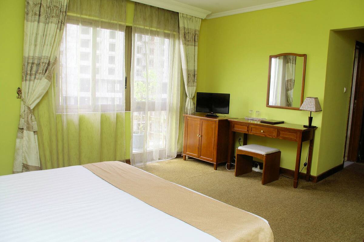 A hotel room with a bed, a desk, a television, and a mirror.