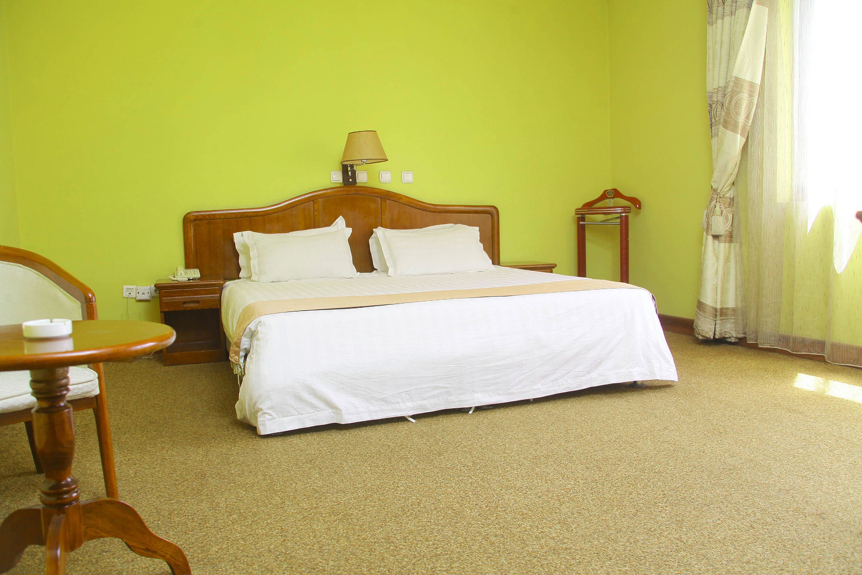 A hotel room with a bed, a nightstand, a chair, and a table.