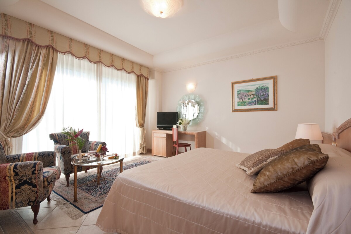 Habitación de hotel con una cama grande, un escritorio con computadora, una silla y un televisor.