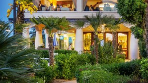 The exterior of the Grand Hotel Galleria with a well-lit entrance, a two-story structure, and lush greenery surrounding the building. - Grand Hotel Gallia (Cervia)