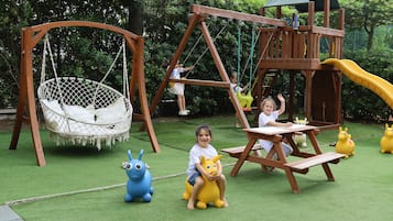 Children can play on the swing set, slide, and hang from the hanging swing in this outdoor play area.