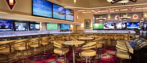 A bar area with multiple screens, bar stools, and a patterned carpet.