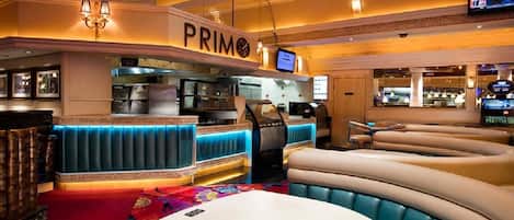 A restaurant with a curved seating area, a bar, and a counter with a 'PRIM' sign.
