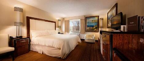 A hotel room with a large bed, bedside lamps, a desk, a chair, a television, and a painting on the wall.