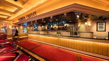 A hotel lobby with a cashier area, red carpeted seating, and a ceiling with intricate designs.