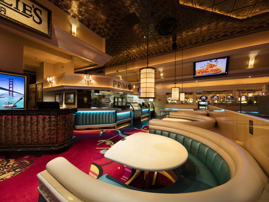 A lounge area with a bar, seating, and a television displaying a pizza.