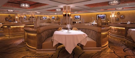 A luxurious dining area with a round table, elegant seating, and ambient lighting.