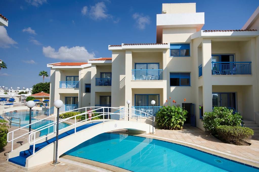 A hotel with a swimming pool, a bridge, and multiple balconies.
