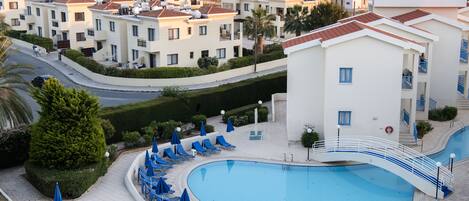 Un resort con piscina, sillas de descanso y vistas al mar.