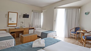 Habitación de hotel con dos camas, un escritorio, una silla y una mesita con fruta.