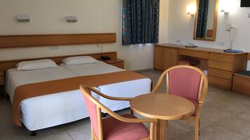 A hotel room with two beds, a desk, a chair, a mirror, and a window with curtains.