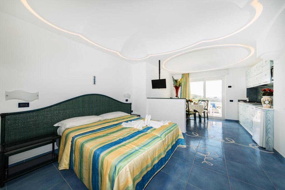 A hotel room with a bed, a desk, a chair, and a view of the outside.