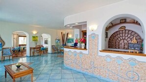 A hotel lobby with a reception desk, seating area, and a tiled floor.