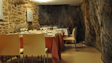 A dining area with stone walls, tables set with wine glasses, and chairs.