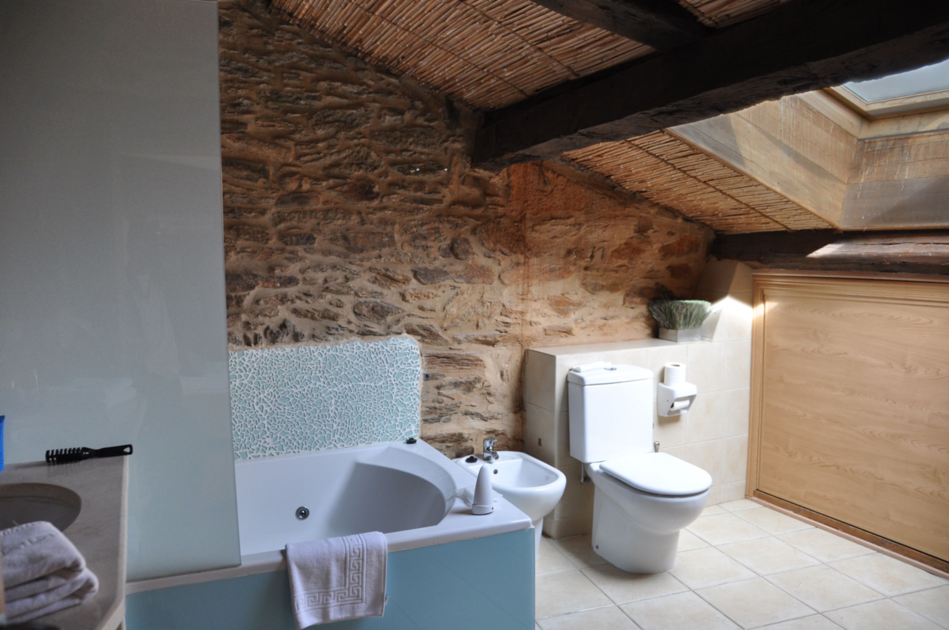 Un baño con pared de piedra, una bañera, un lavabo, un bidé y un inodoro.