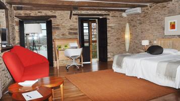 A room with a bed, a red chair, a desk, and a window.