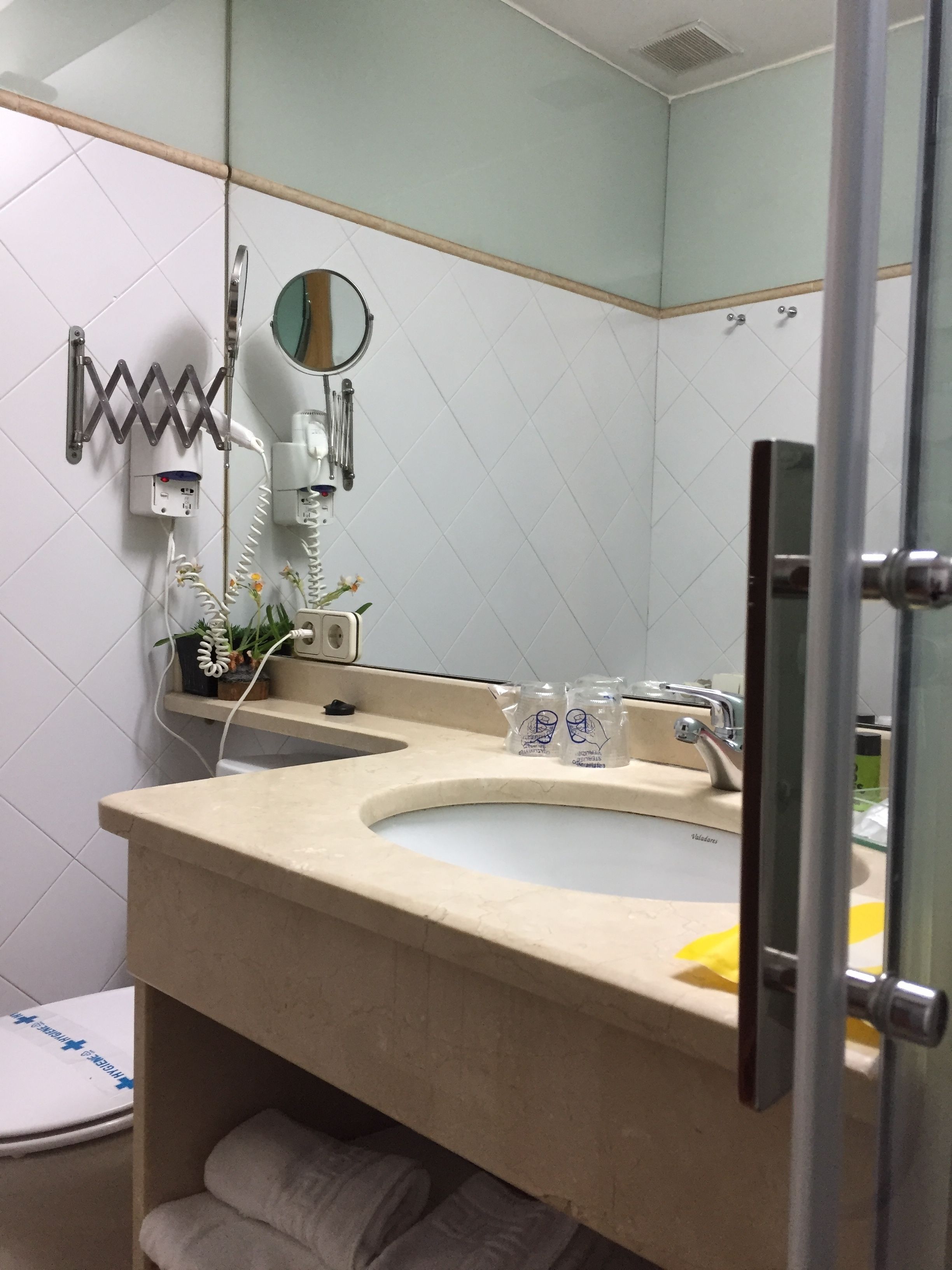 Une salle de bain équipée d’un lavabo, d’un miroir, d’un porte-serviettes et d’un sèche-cheveux.