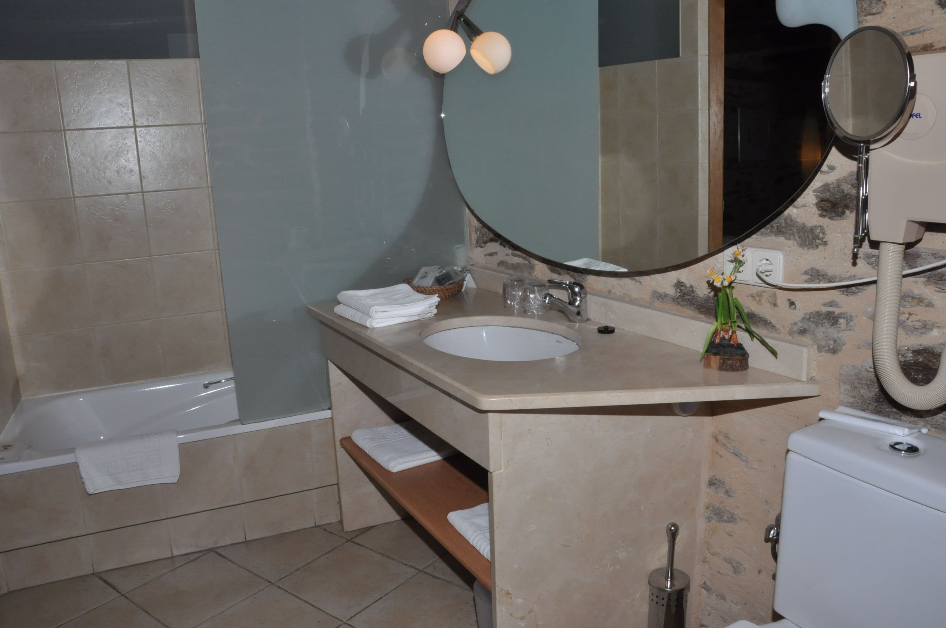 A bathroom with a bathtub, a sink, a mirror, and a toilet.