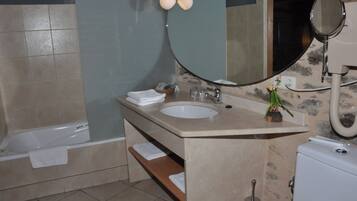 A bathroom with a bathtub, a sink, a mirror, and a toilet.