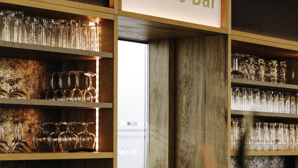 Un espace bar avec des étagères remplies de verres et une enseigne indiquant « Moier’s Bar ».