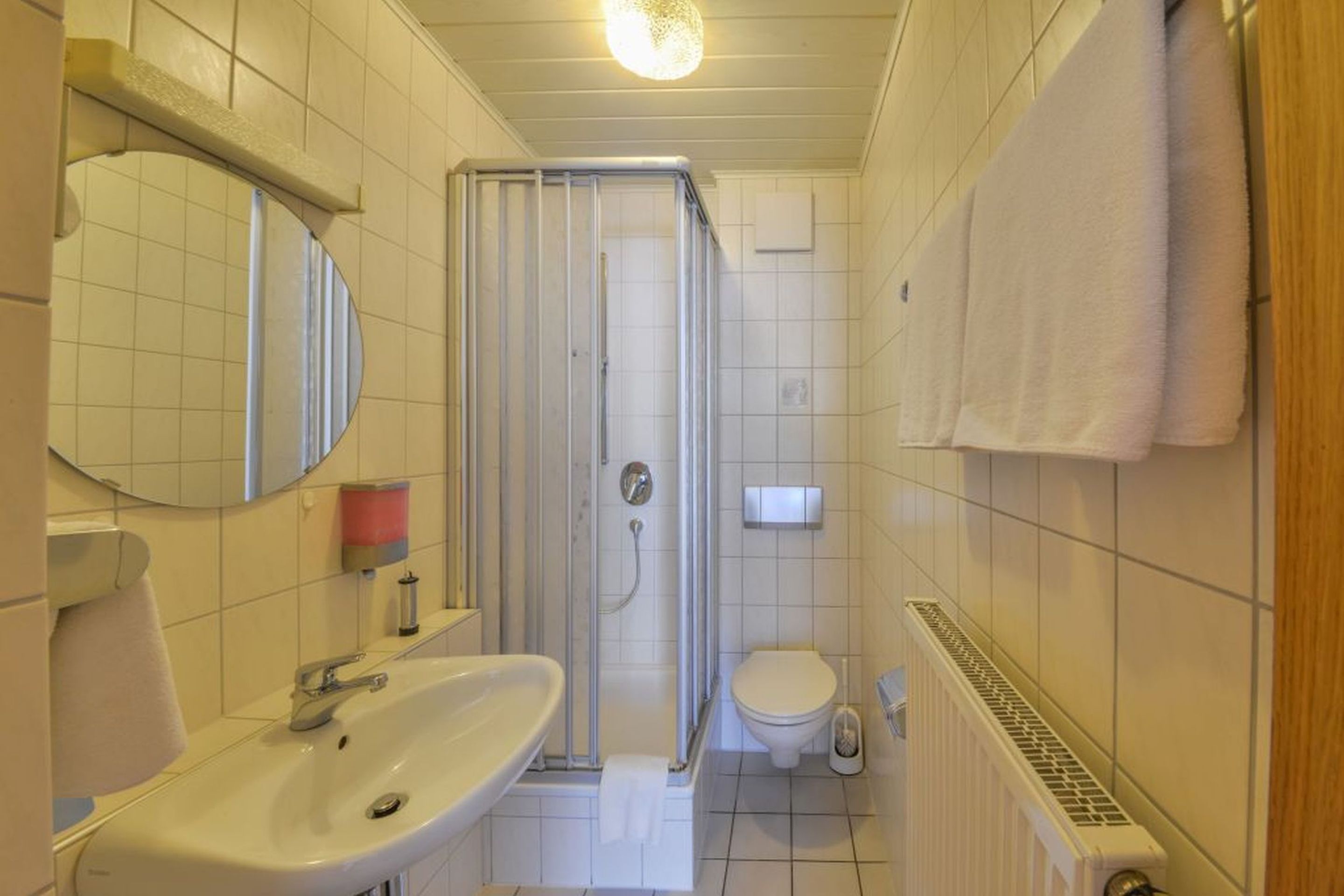 Ein Badezimmer mit Waschbecken, Spiegel, Toilette, Dusche und Handtuchhalter.