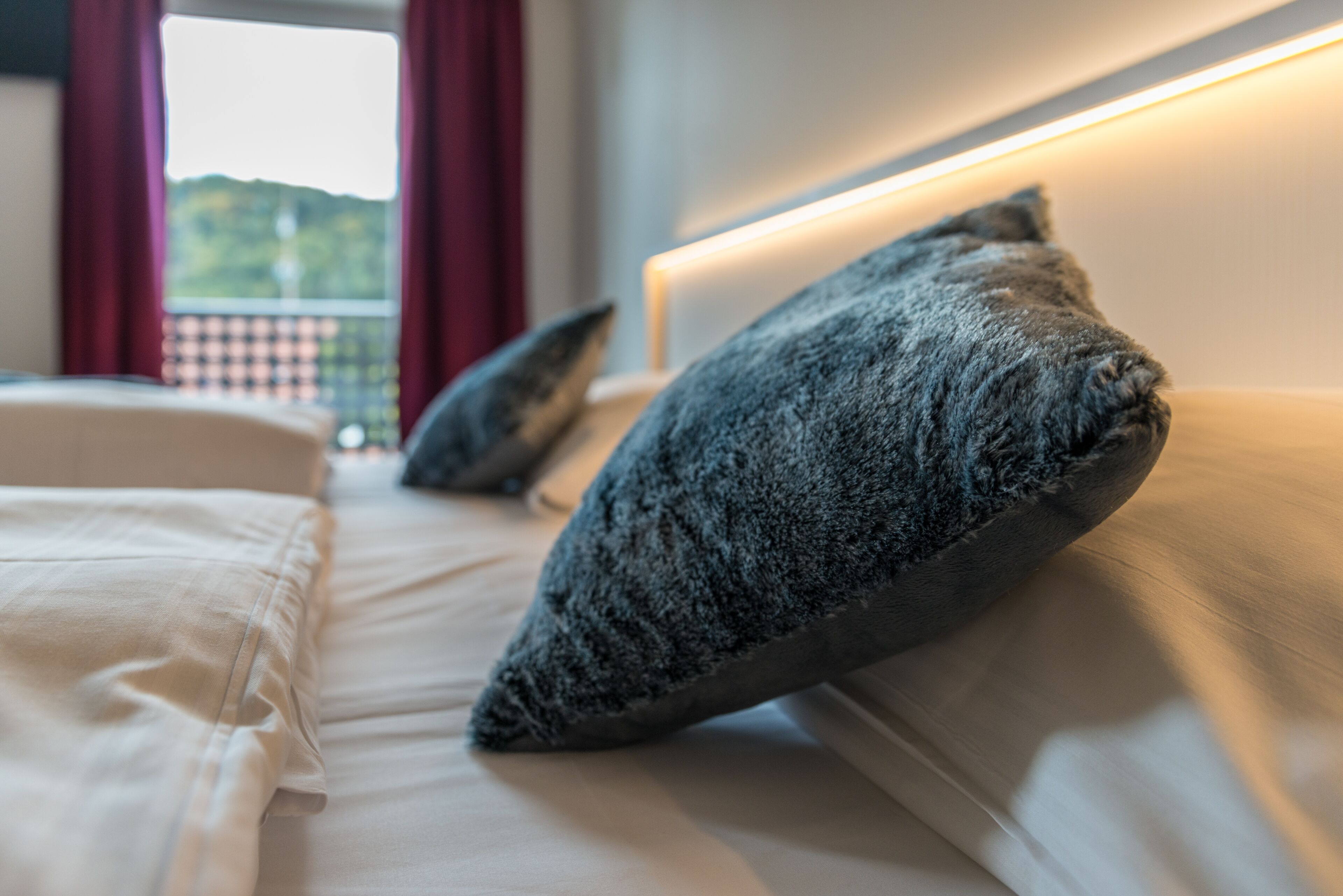 Et hotelværelse med seng, puder og udsigt til naturen.