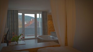 Une chambre avec une grande fenêtre, une baignoire et un plancher en bois.