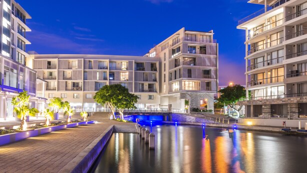 Ett modernt hotell med flera våningar, en central innergård med en fontän och väl upplysta balkonger.