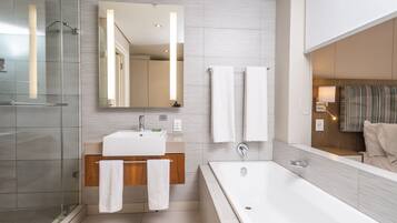 Un baño moderno con cabina de ducha de vidrio, tocador de madera, espejo grande y bañera independiente.