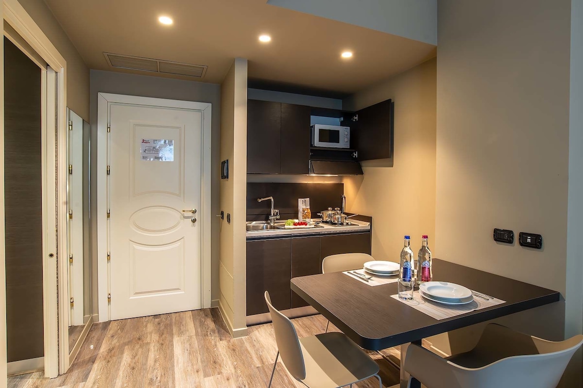 A compact kitchen with a microwave, sink, and a dining area with a table and chairs.