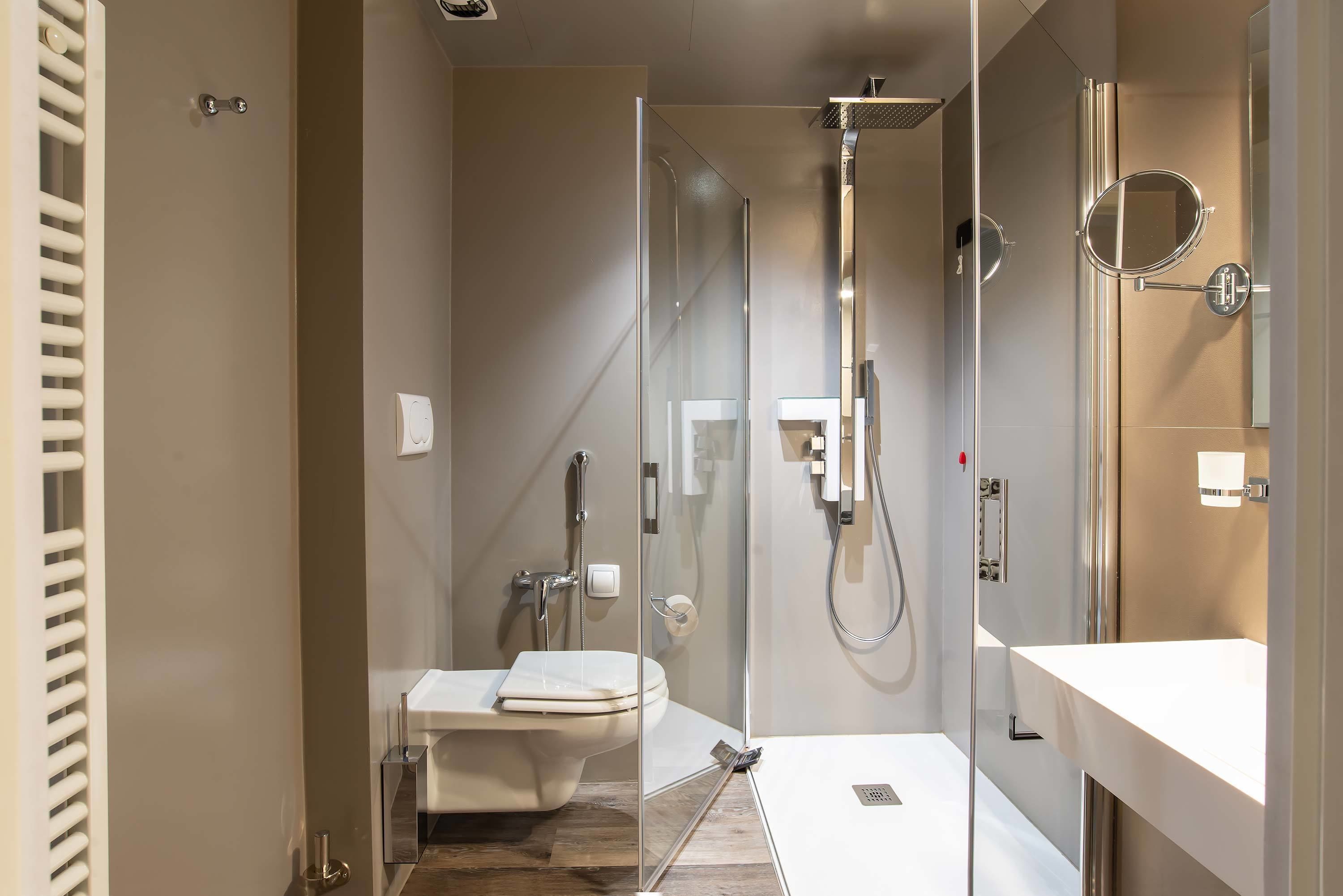 Un bany modern amb dutxa de vidre, un vàter blanc i un lavabo amb mirall.