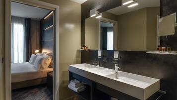 Una habitación de hotel moderna con una cama grande, un lavamanos doble y un espejo.