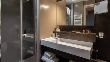 Un bagno moderno con cabina doccia in vetro, lavandino bianco e uno specchio grande.