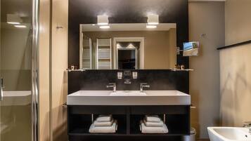 A modern bathroom with a double sink vanity, a large mirror, and a glass shower enclosure.