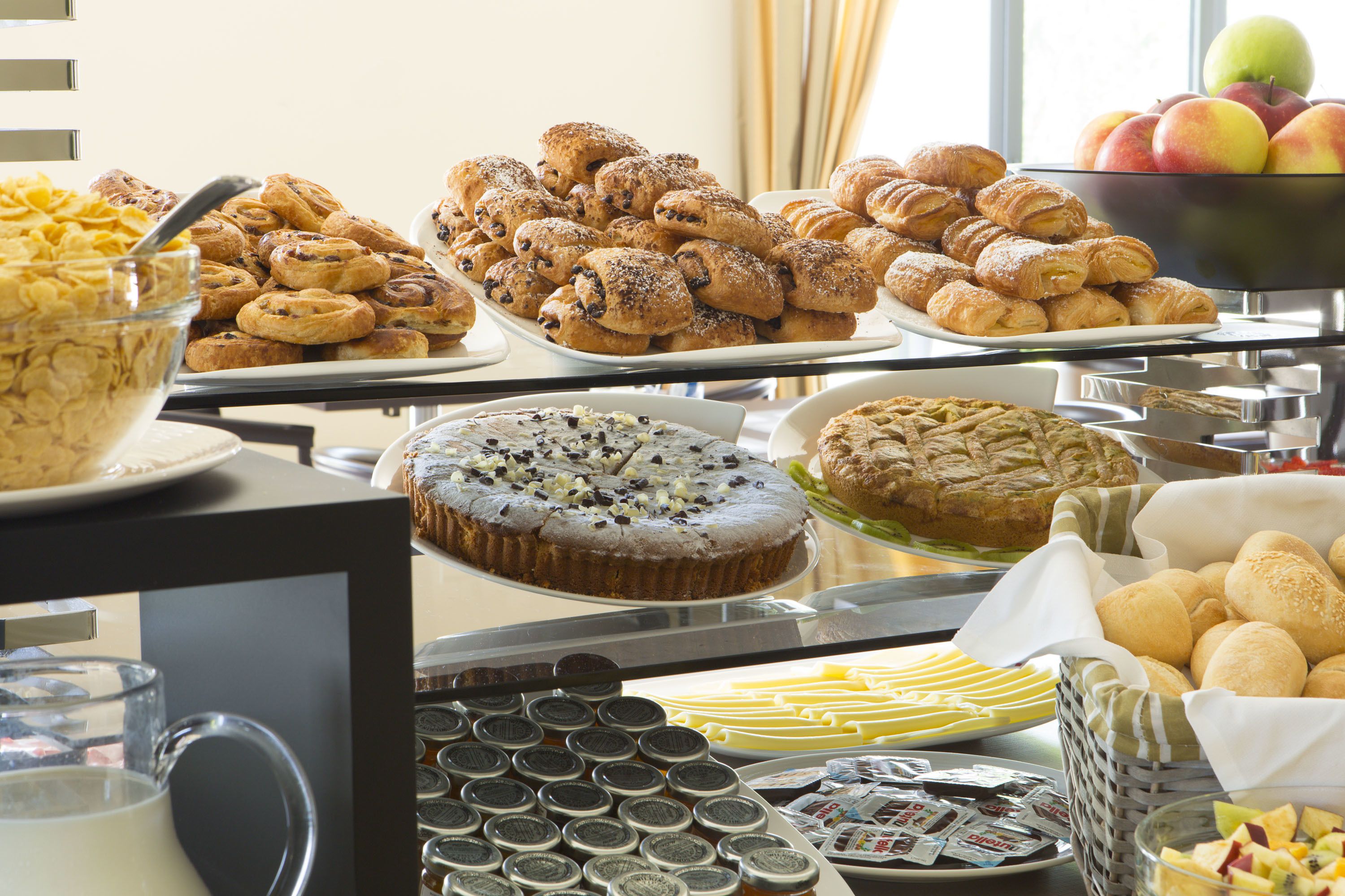 A buffet with various baked goods, including pastries, cookies, and a cake.