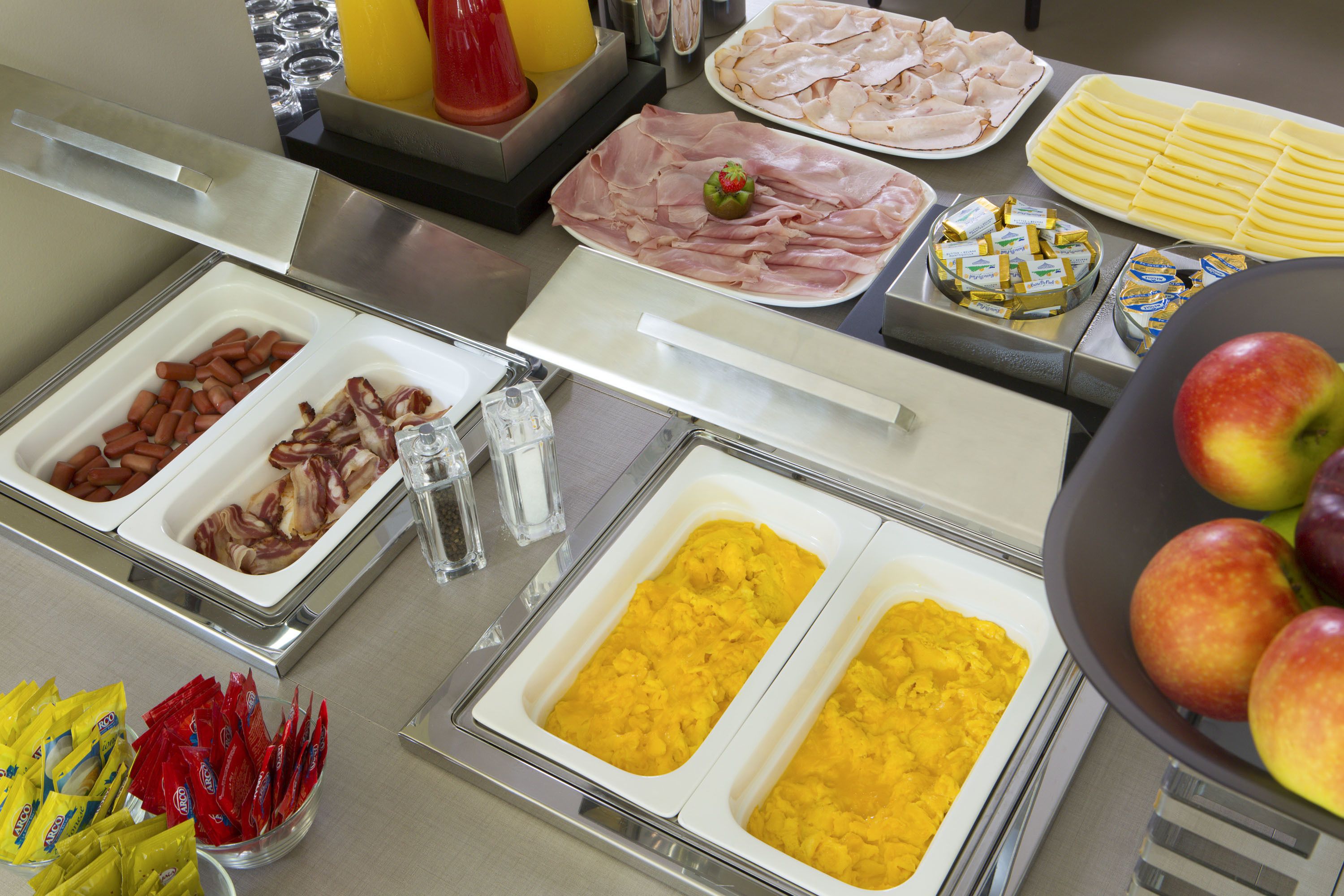 Ein Buffet mit verschiedenen Speisen, darunter Fleisch, Obst und Soßen.