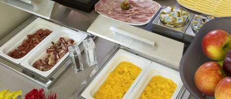 A buffet with various food items including meats, fruits, and condiments.