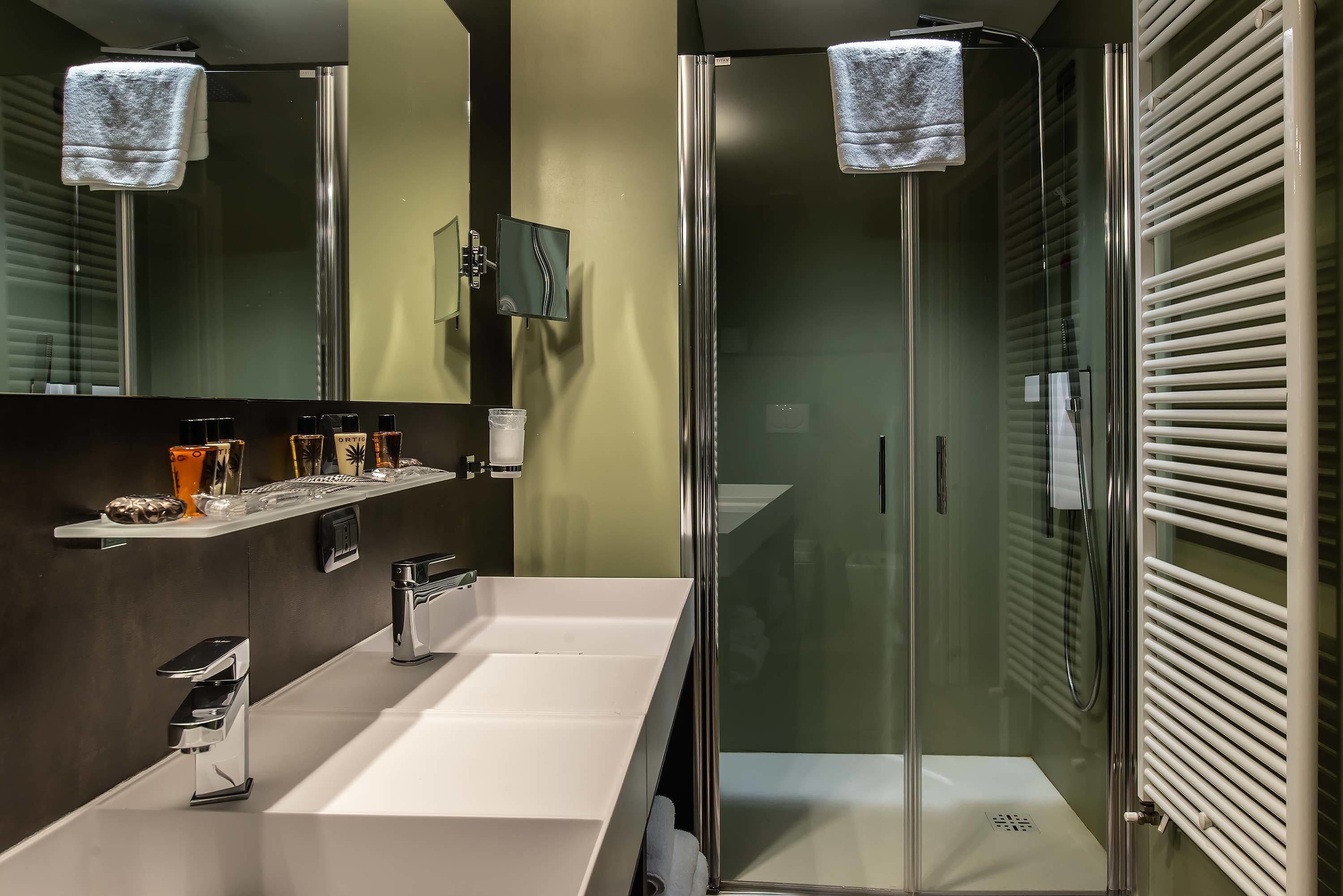 Ein modernes Badezimmer mit einem großen Spiegel, einem weißen Waschbecken und einer Duschkabine aus Glas.