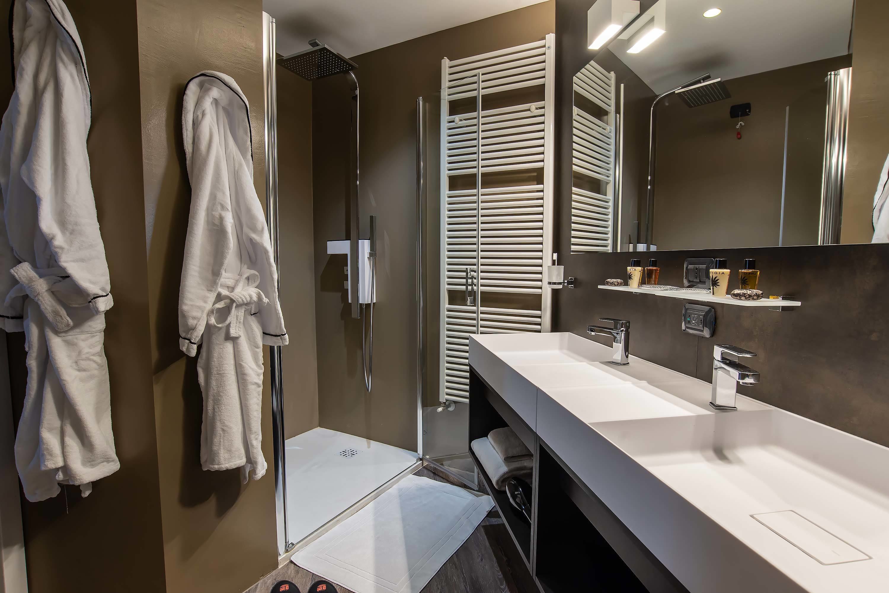 Une salle de bain moderne dotée d’une douche à l’italienne, d’un grand miroir et d’un meuble-lavabo avec deux vasques.
