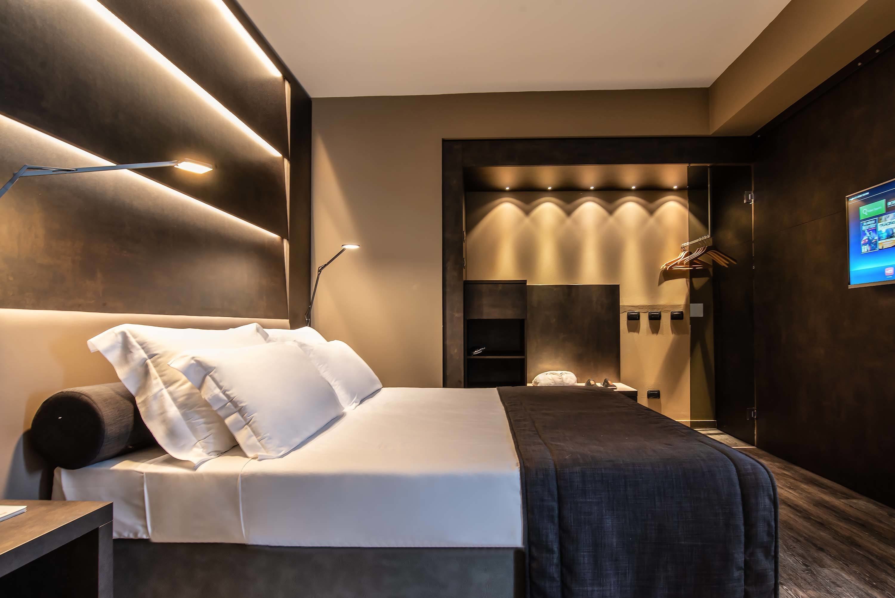 Une chambre d’hôtel moderne avec un lit bien fait, un bureau et un téléviseur fixé au mur.