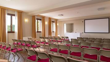 A conference room with rows of chairs, a whiteboard, and a projection screen.