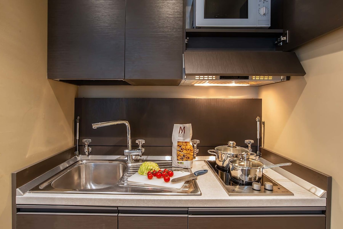A modern kitchen with stainless steel appliances, a microwave above the stove, and a sink with a cutting board and vegetables.