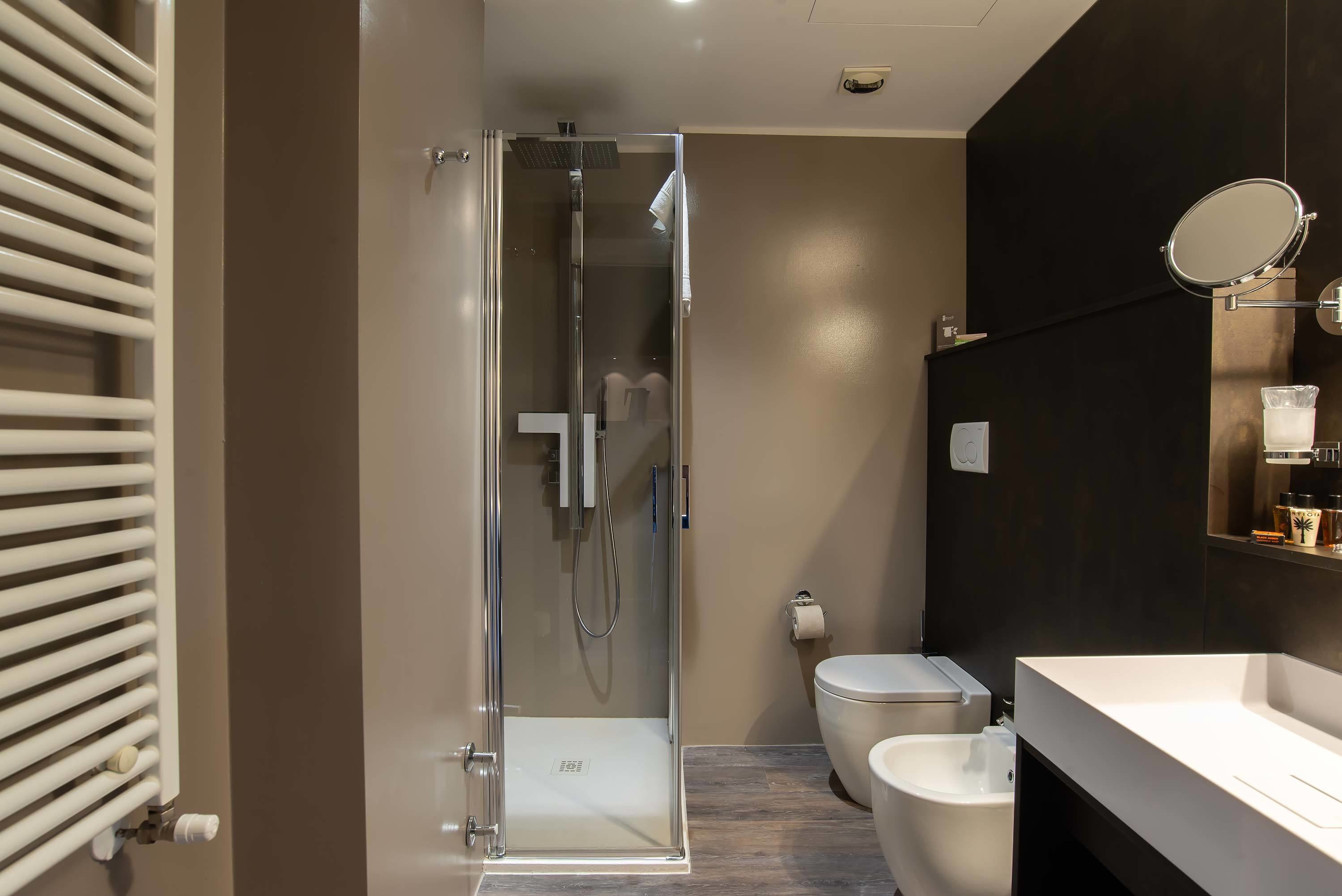 Un baño moderno con ducha envuelta en vidrio, inodoro y tocador con espejo.