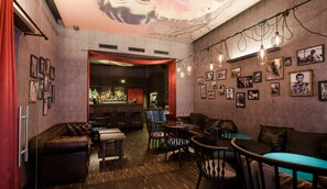 A bar area with multiple seating options, including leather sofas and chairs, a bar counter with a variety of bottles, and a wall adorned with framed pictures. - Casati Hotel – Adults Only (Budapest)